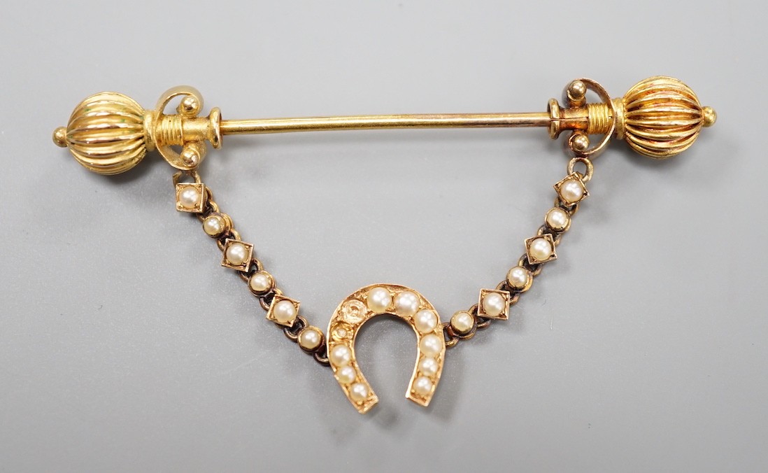 An early 20th century yellow metal and seed pearl horseshoe swag jabot pin, 59mm, gross weight 4.9 grams (pearl missing).